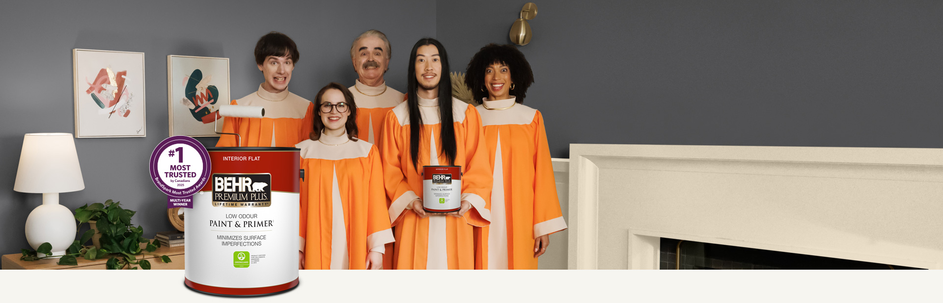 Choir standing in a painted living room and holding a can of Behr Premium Plus Interior Flat Paint