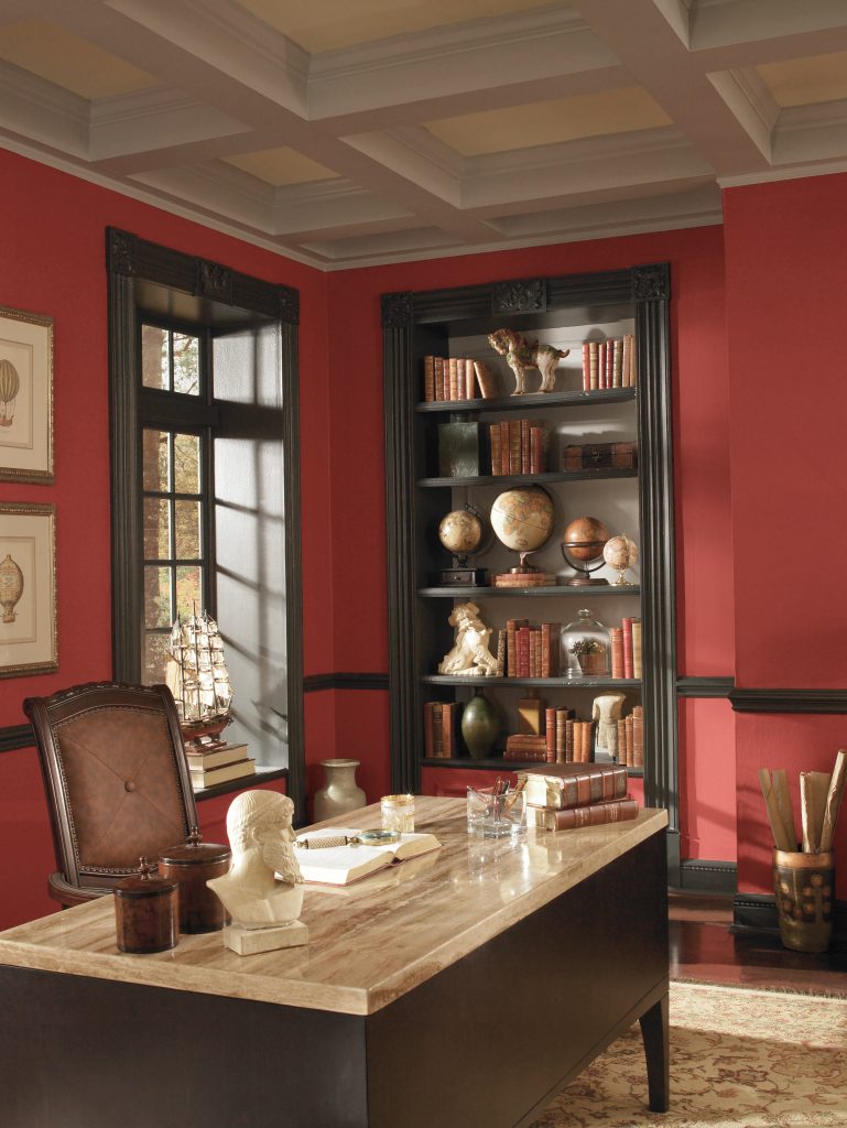 A home office/study room with walls painted in a bold, orange-tinged red colour 