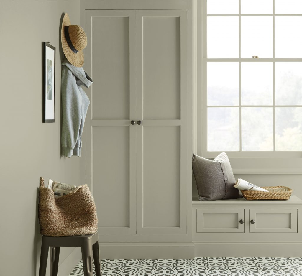 A built-in storage and seating area all painted in a grey-green colour