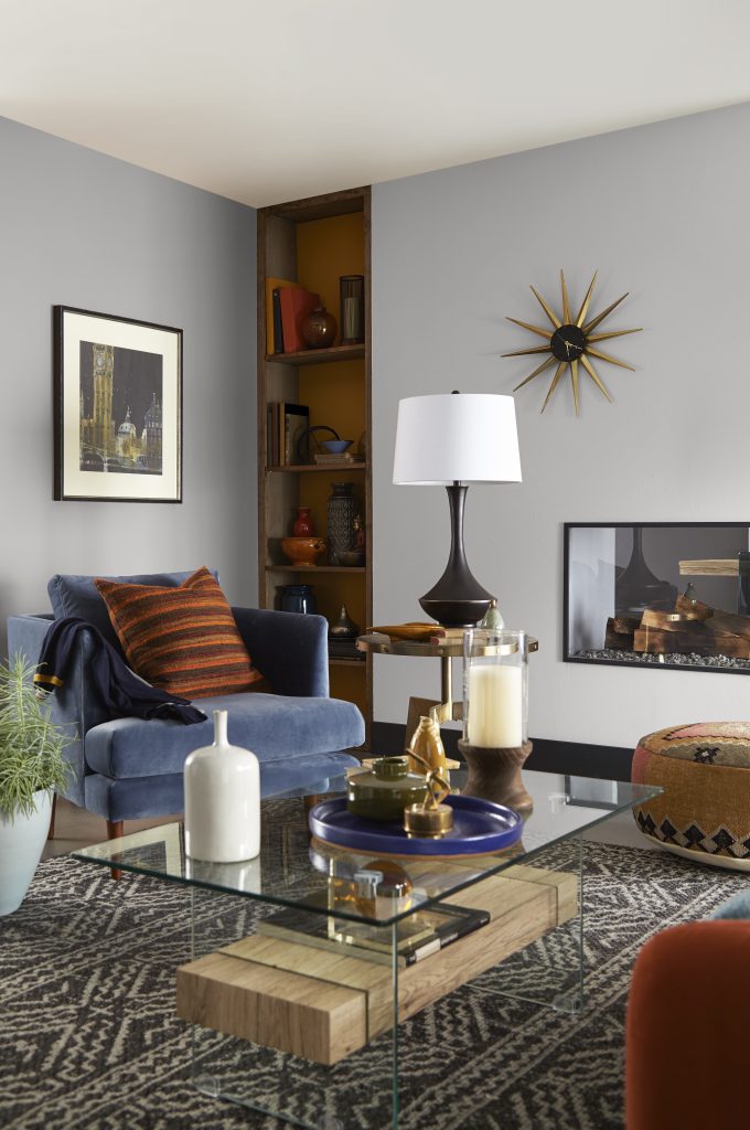 A retro living room with walls painted in a light grey colour, styled with lots of different furniture and décor pieces 