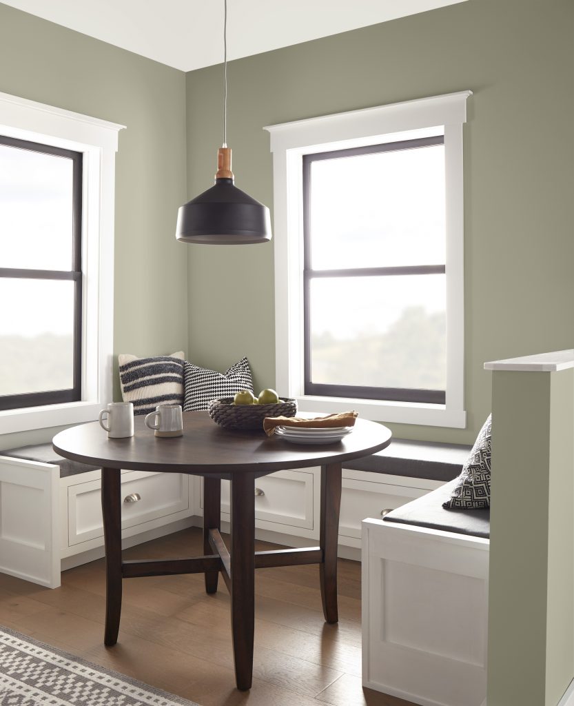 A corner kitchen and dining nook with walls painted in a grey-green colour