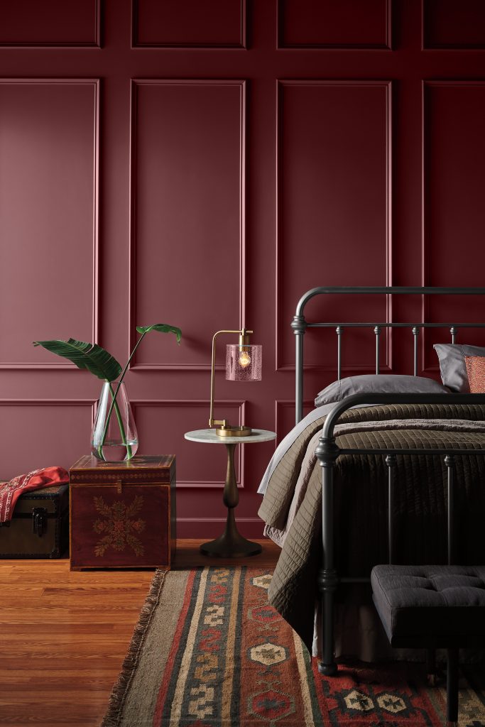 A moody bedroom with walls painted in a deep burgundy colour