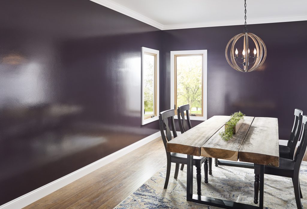 A dining room with walls painted in a purple colour in a hi-gloss sheen
