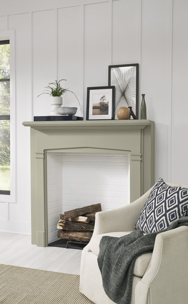 A fireplace mantle and frame painted in a light grey-green colour