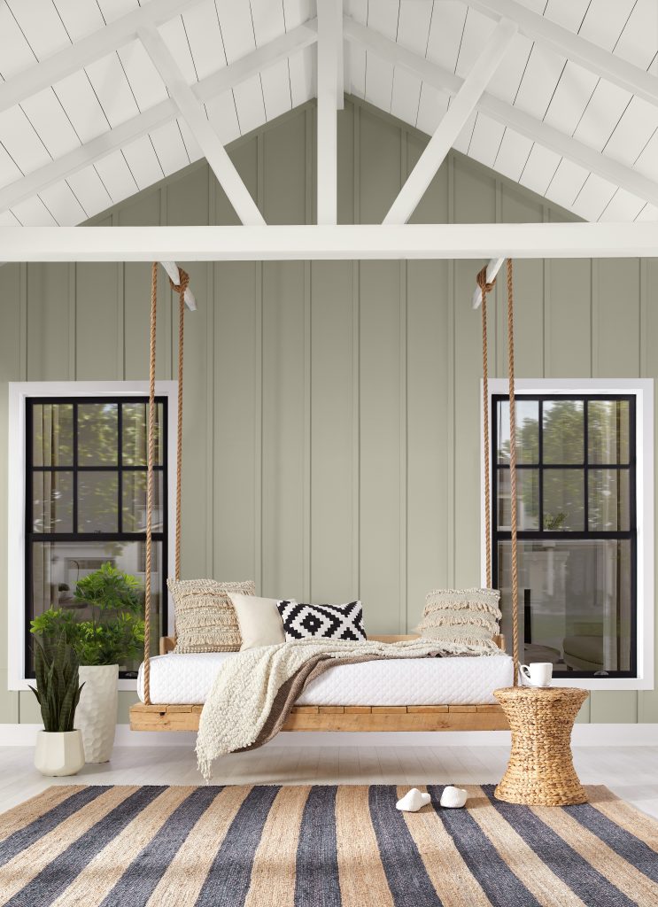A boho porch with grey-green siding and a wooden patio swing
