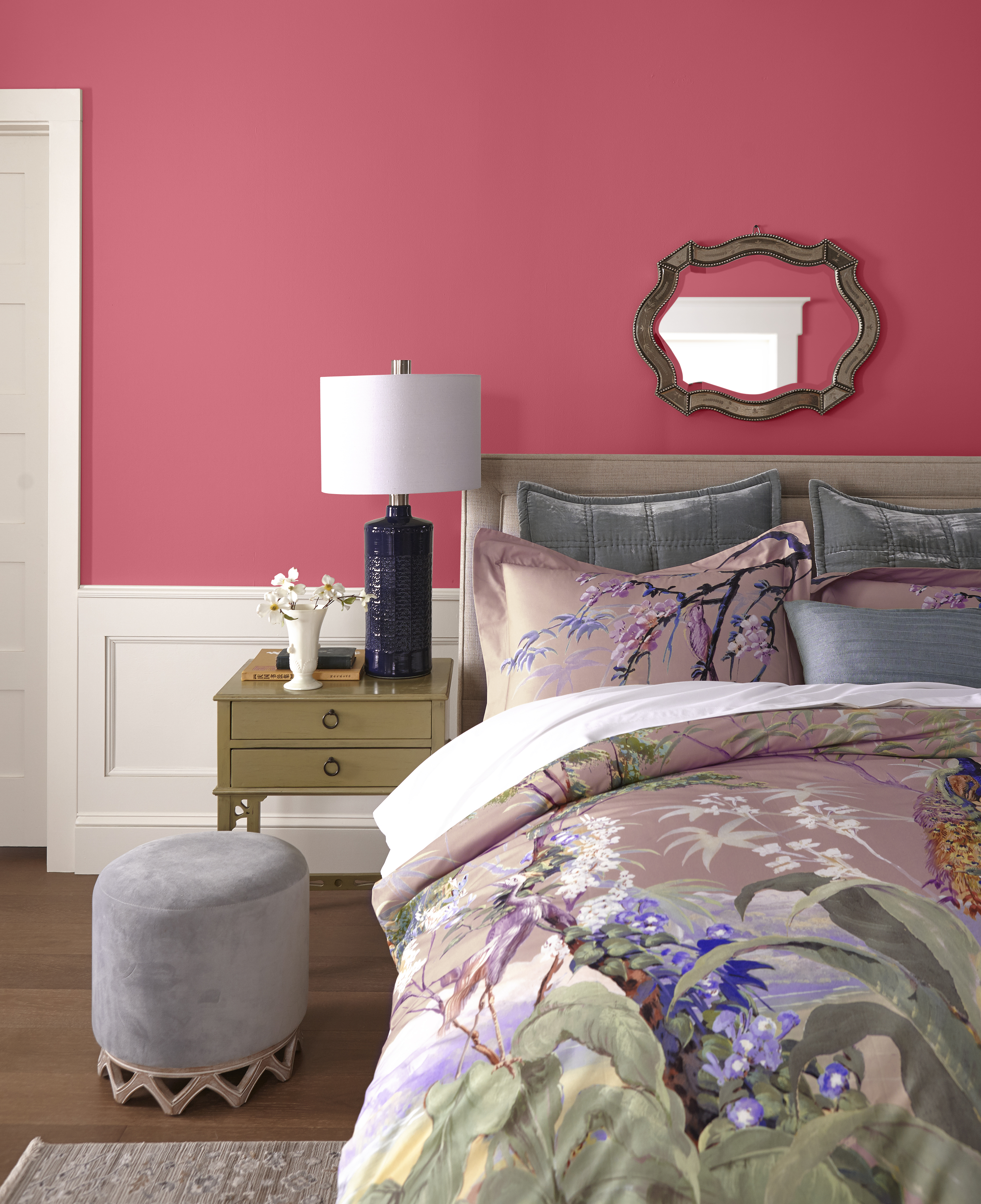 A bedroom with floral bedding and walls painted in a warm red-pink hue.