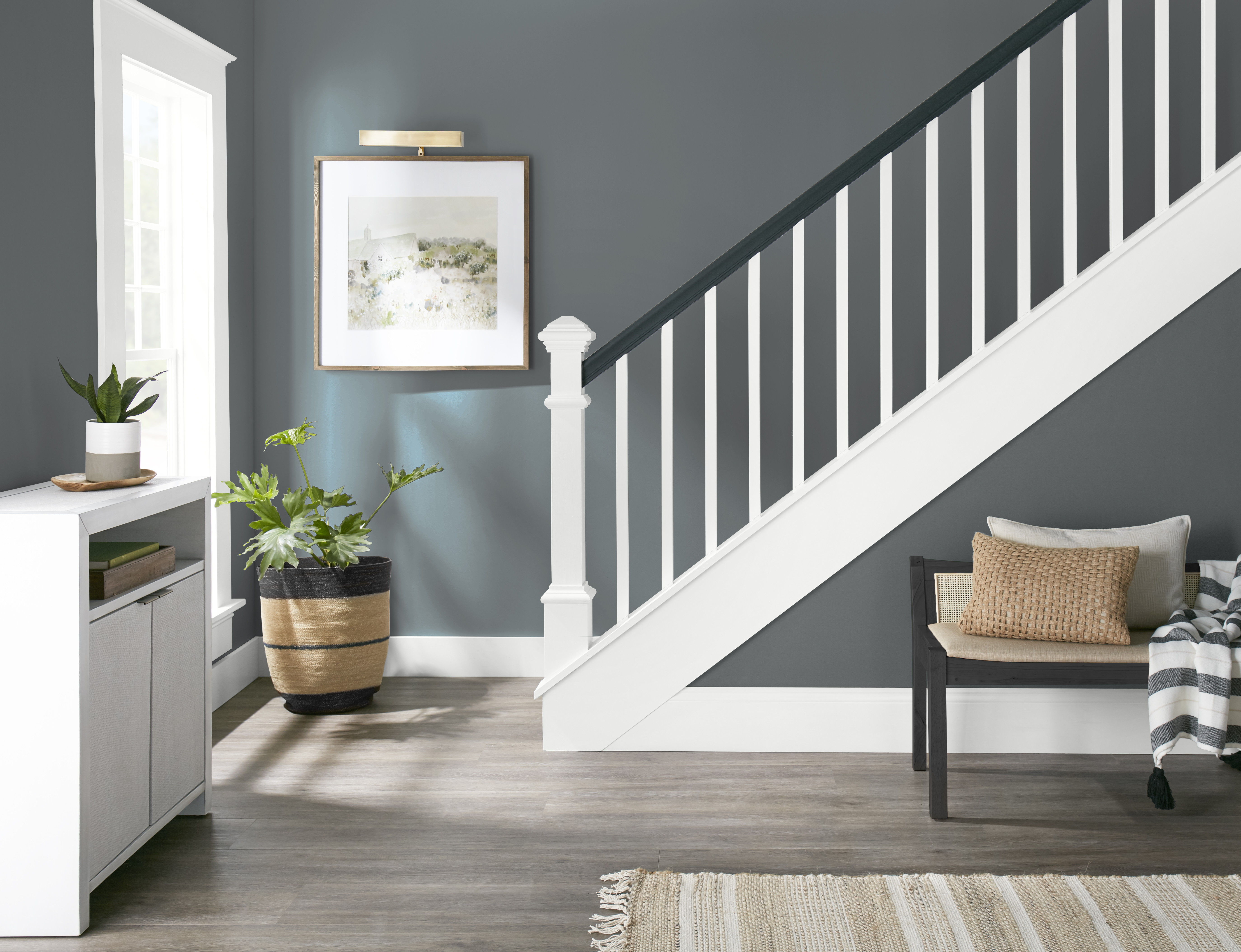 An entryway with stairs going to a second floor with walls painted in a grey-toned blue