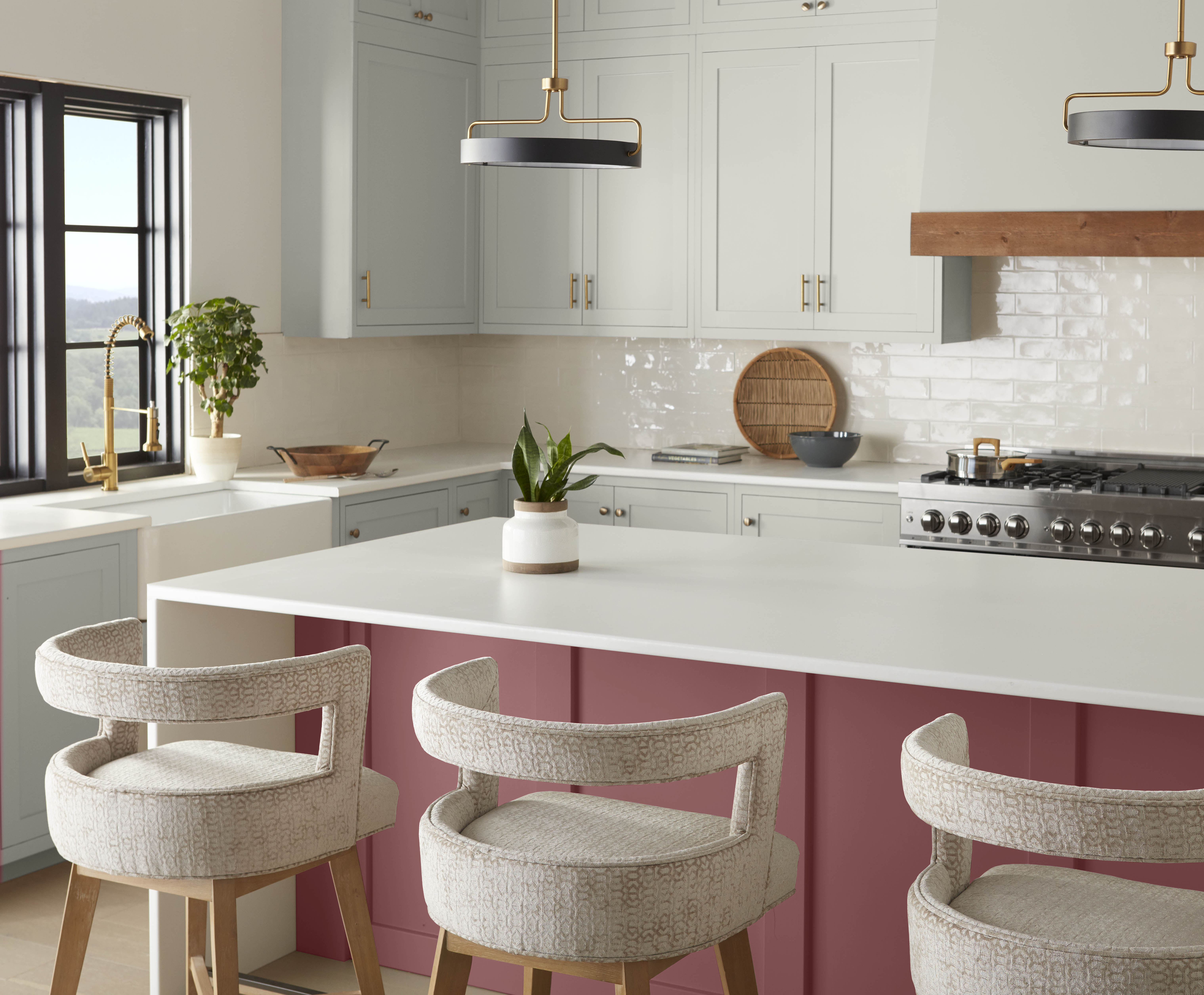 A kitchen with grey cabinets and an island painted in shaded warm red hue.