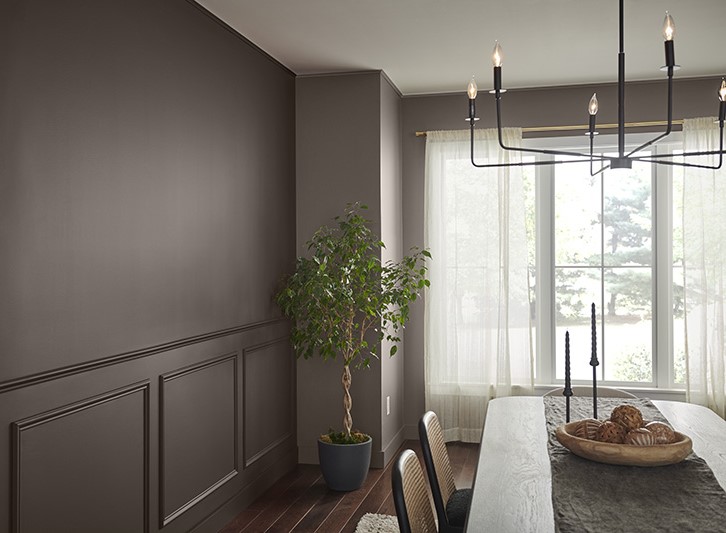 A traditional dining room with dark chocolate brown accent wall that makes it feel inviting and sophisticated. 