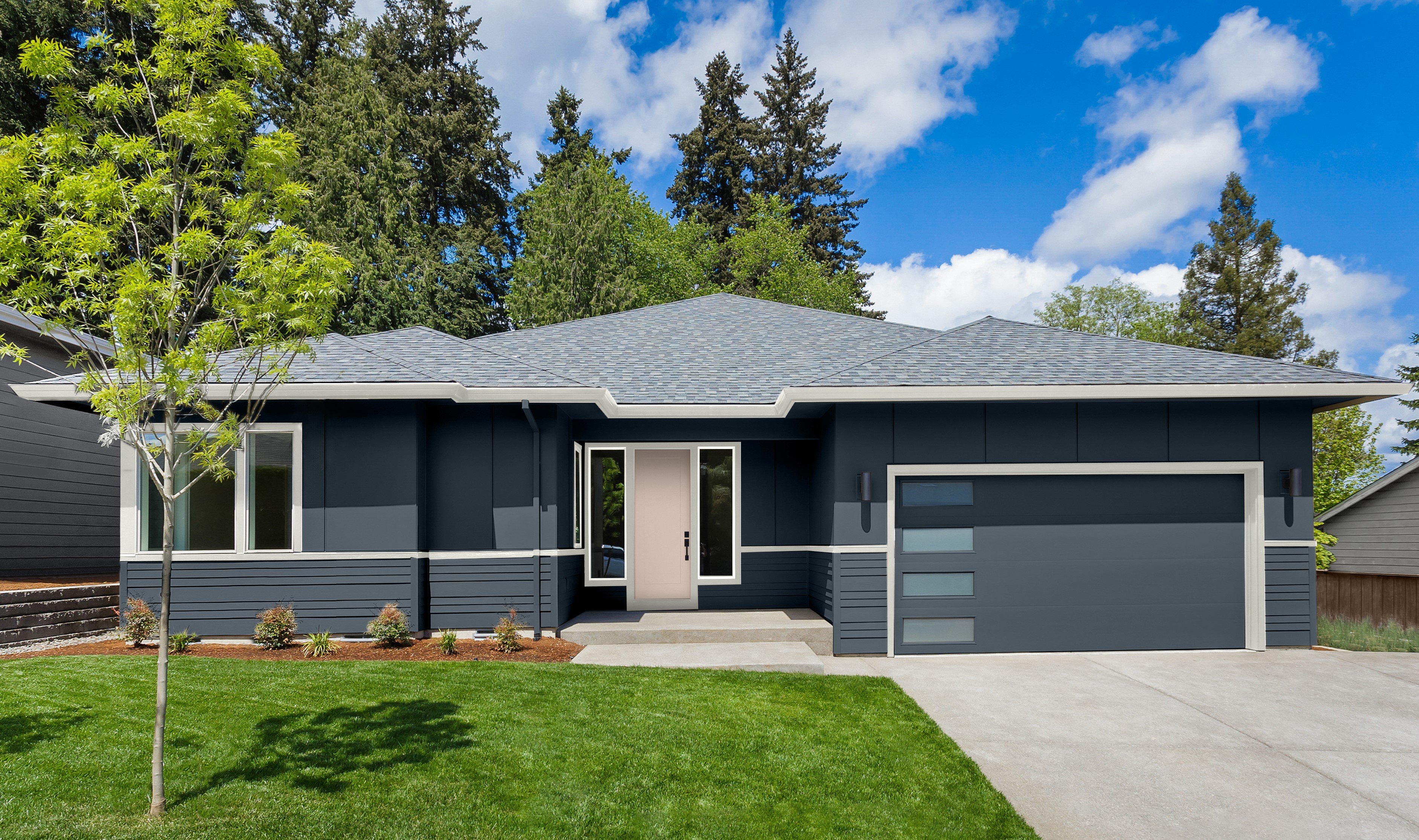 The exterior of a house with stucco and siding in Midnight Blue, creating a bold and sophisticated look. The trim is in Whisper White, and the door is painted in Seaside Villa, a soft, welcoming colour.