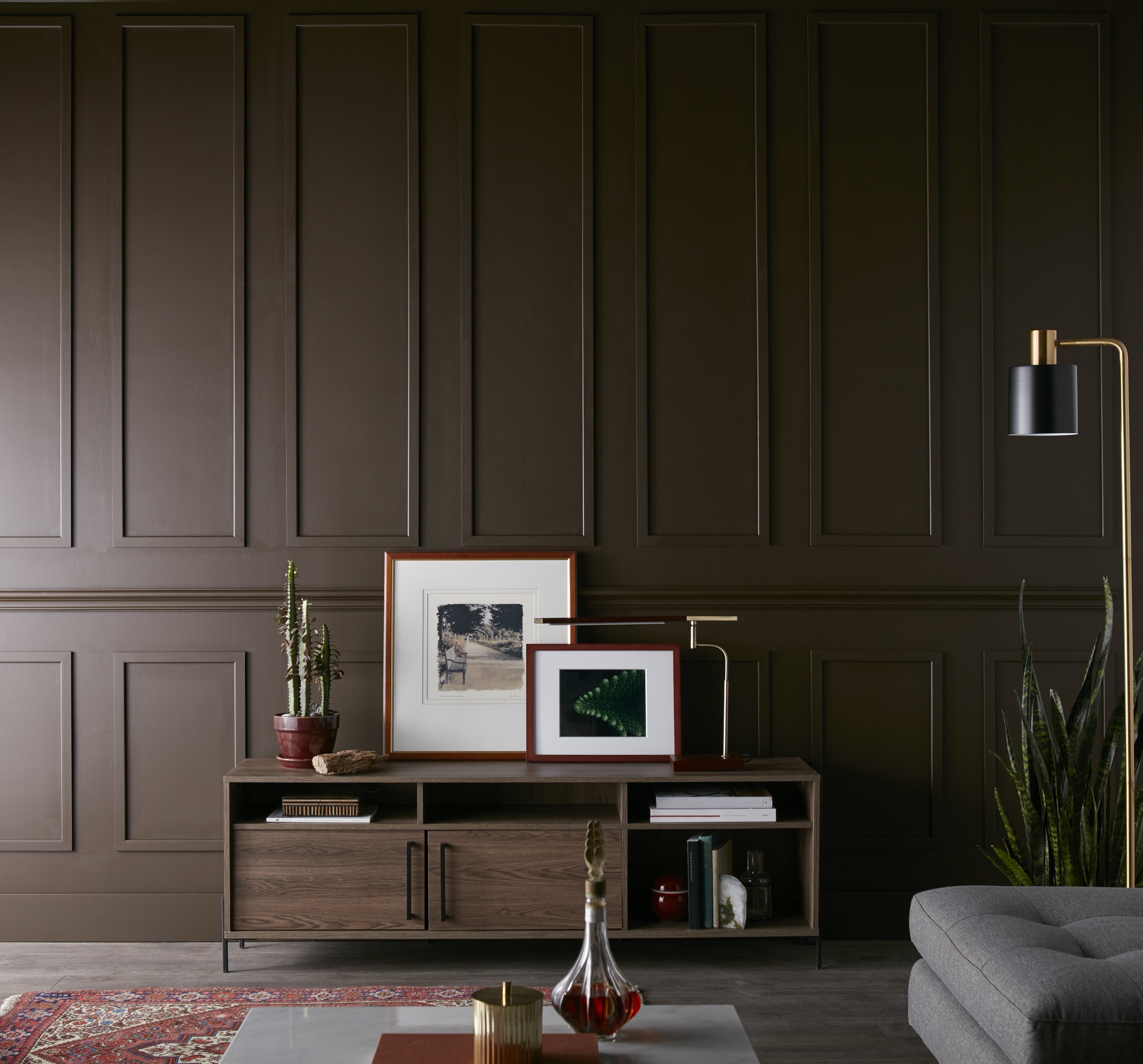 A contemporary living room with panelling details and a dark brown paint colour application.