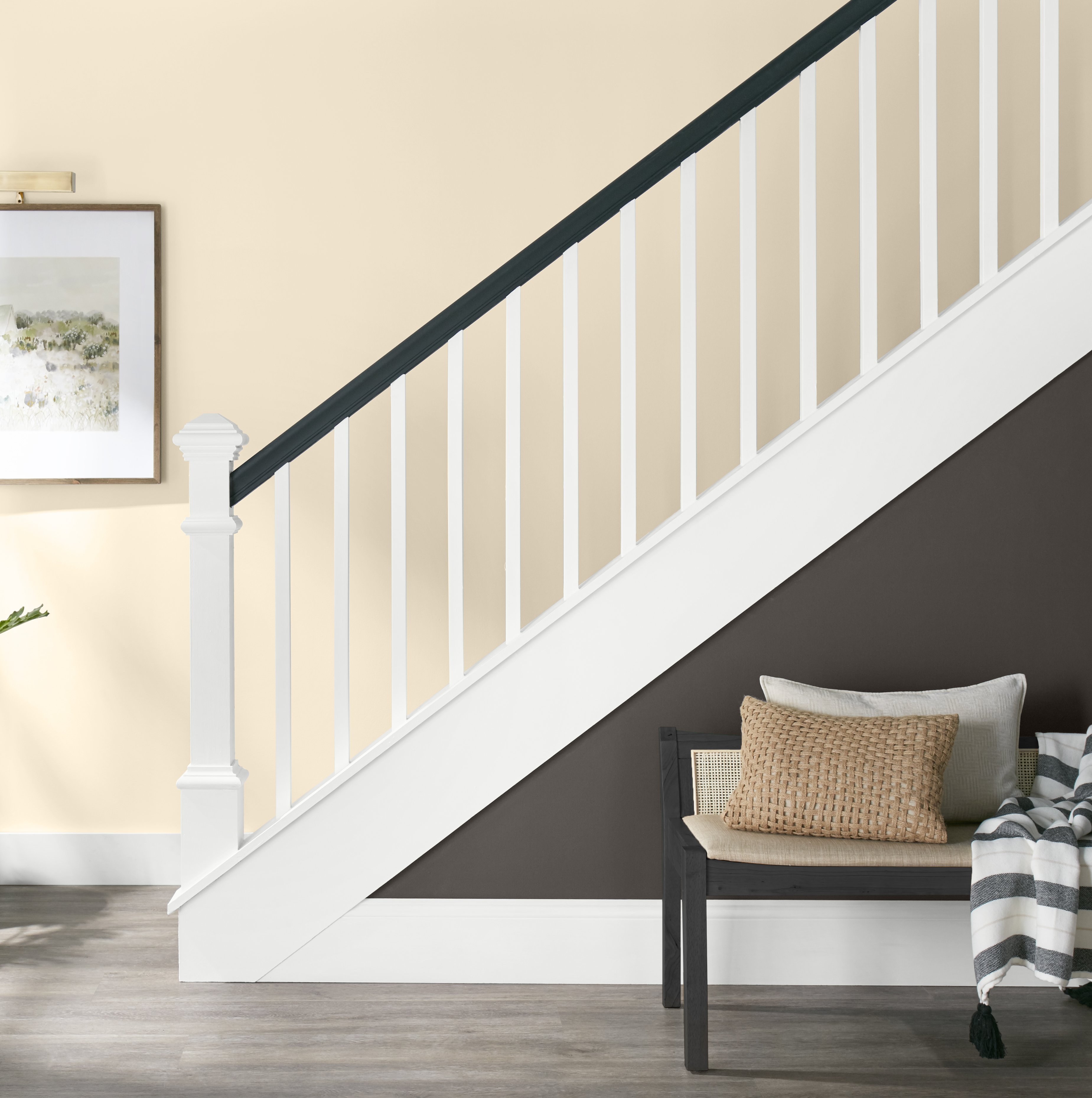 An entryway showing a staircase with the wall behind painted in a soft white hue.