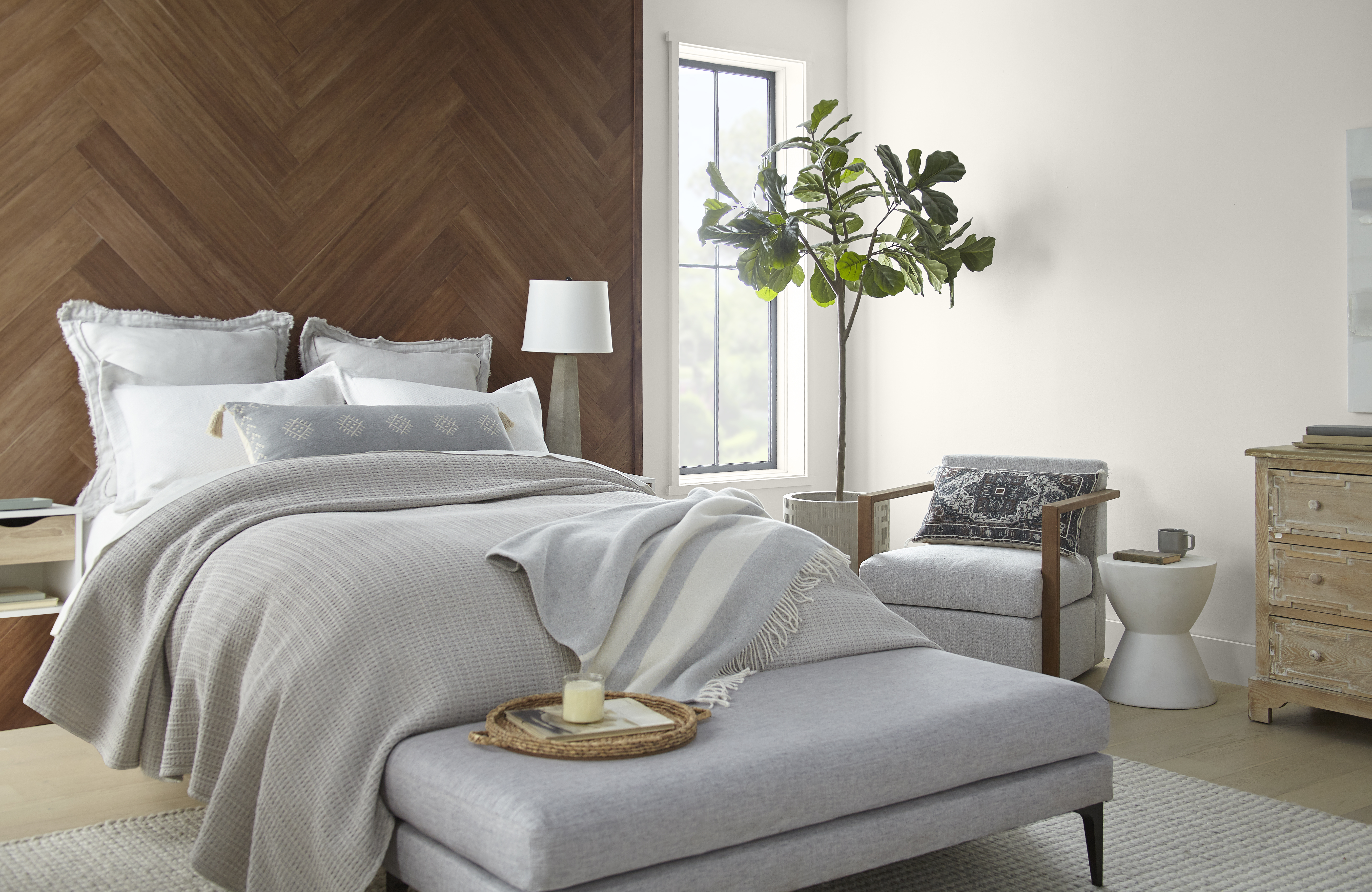 A bedroom with a wood headboard and walls painted in a pearly white hue.