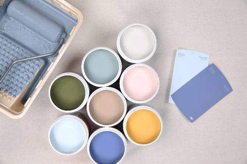 Image shows multiple 237 ml opened paint samples with different colours, to the left of the samples is  a paint tray with a roller, and to the right are two single paint chips.