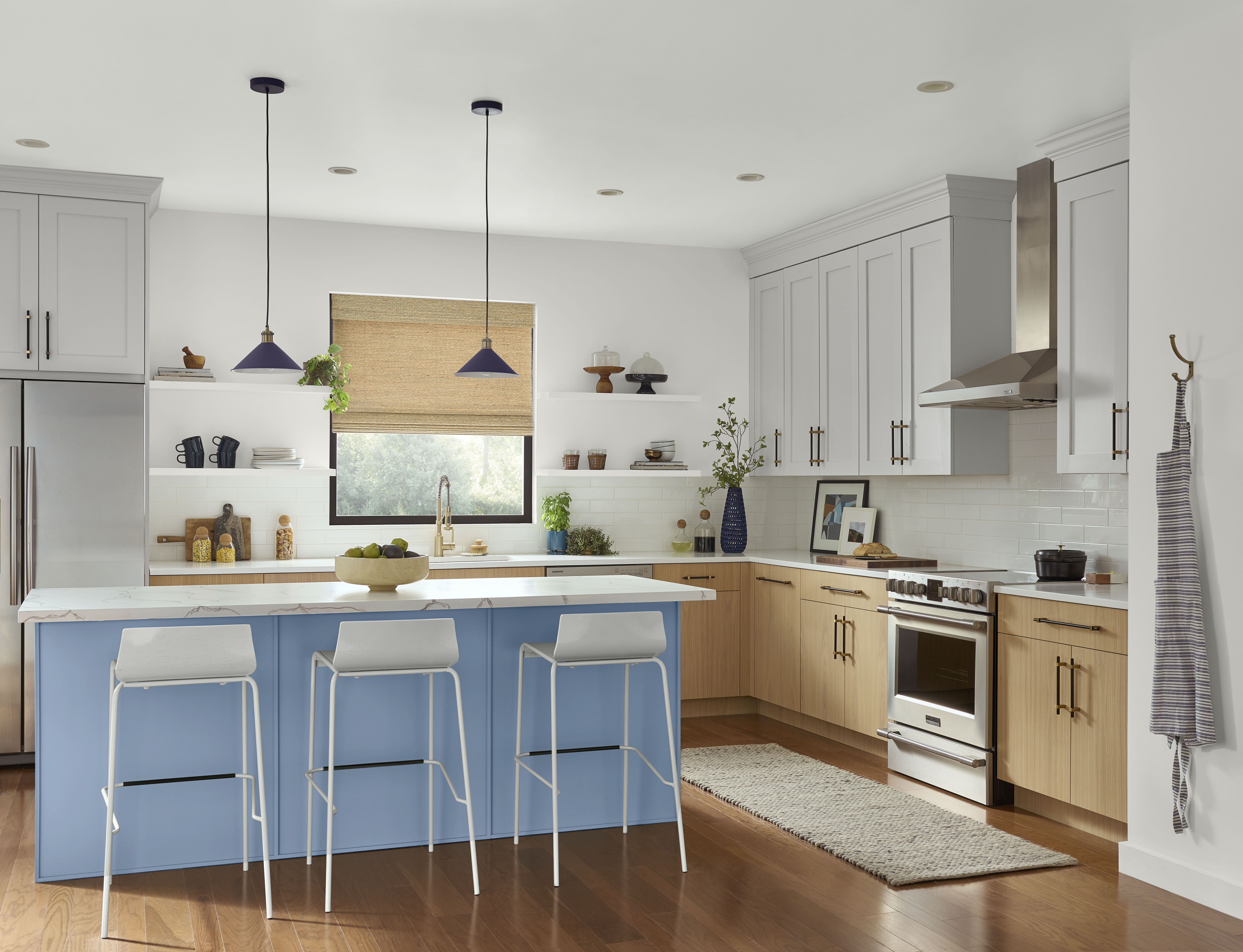 A full kitchen featuring a light blue kitchen island as the focal point. The cabinets are two-toned, combining light natural wood with another complementary light colour, creating a modern and inviting space.